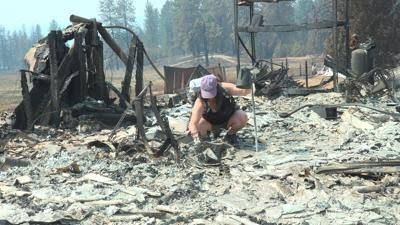 A resident sifts through the charred ruins of a destroyed home in Spokane following the recent wildfires.