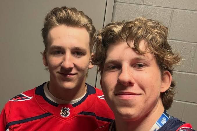 Cole Hutson and Andrew Cristall standing together in Washington Capitals home jerseys at the NHLPA Rookie Showcase.