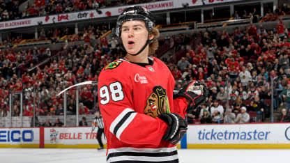 Connor Bedard in a Chicago Blackhawks jersey looking toward the ice during a game.