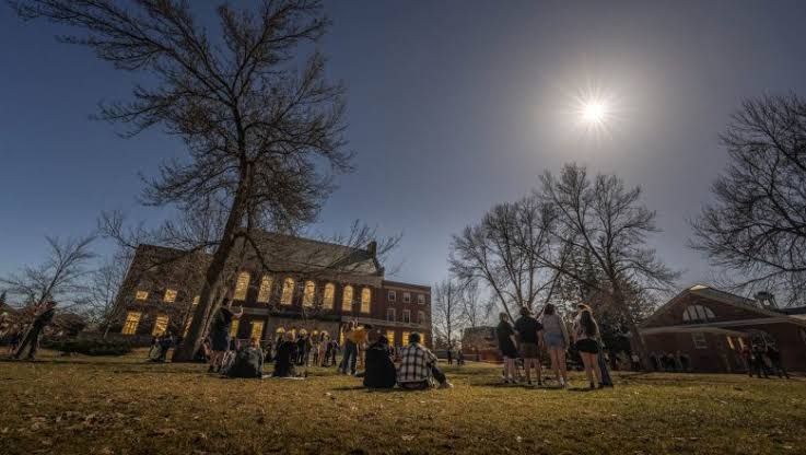 A partial solar eclipse showing the moon blocking a portion of the sun against a bright sky.