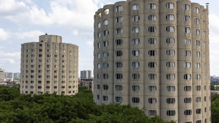 The crescent-shaped Hilliard Towers apartments showing unique lozenge-shaped windows against a clear sky.