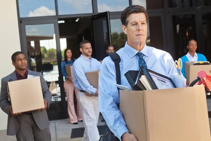 Workers clearing out an office space with boxes during a layoff event.