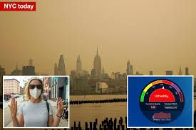 New York City skyline and Empire State Building partially obscured by thick orange wildfire smoke.