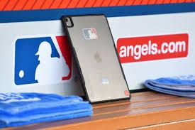 An iPad propped up in an MLB dugout showing a game strategy interface used for scouting and pitch analysis.