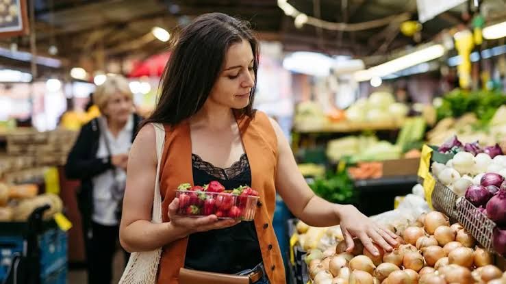Sports dietitian Tatiana Vélez-Burgos holding a container of strawberries at a grocery store.