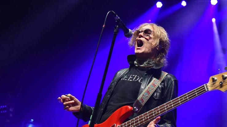 Glenn Hughes performing on stage with a bass guitar during a live rock concert.