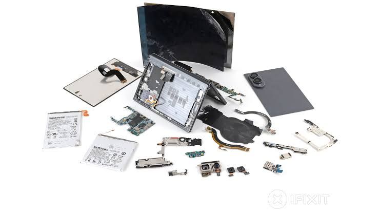 Internal components of a Samsung Galaxy Z Fold 8 exposed on a white workspace during an iFixit repair teardown.