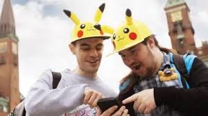 Two Pokémon Go fans holding phones and looking at the screen with shock in front of a street background.