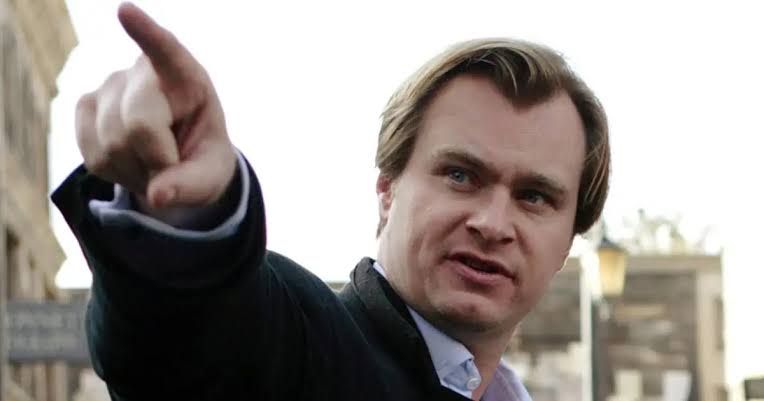 Christopher Nolan standing in front of a dark background, illustrating his role as a prominent Hollywood director.