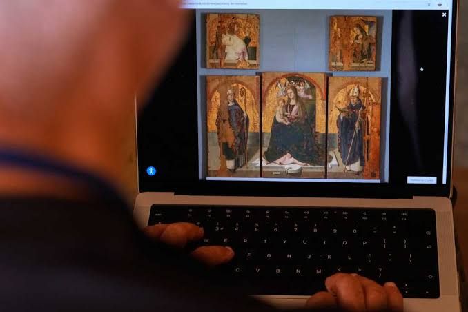 A journalist looks at an Antonello da Messina painting on a computer screen following the museum heist in Sicily.