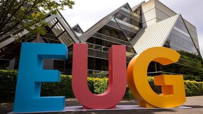 Three bright, six-foot-tall letters spelling EUG standing on a plaza near the Hult Center in downtown Eugene.
