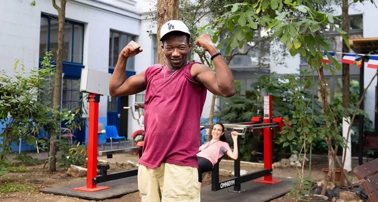 A man using an outdoor exercise machine at a homeless shelter courtyard in Paris.
