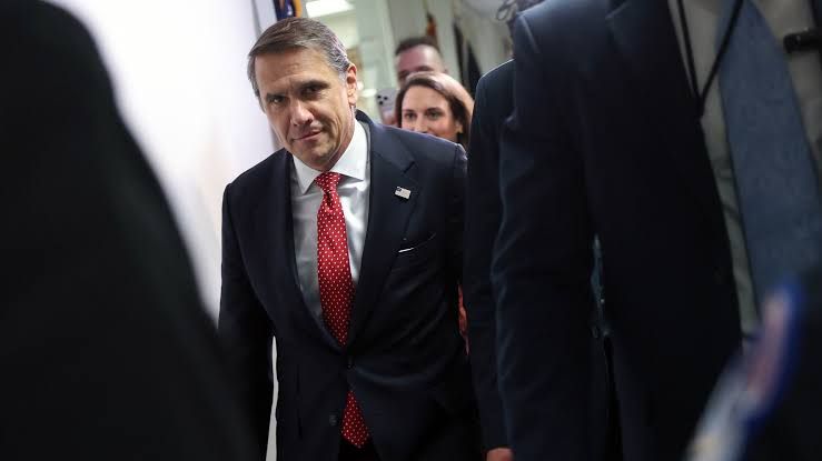 Attorney general nominee Todd Blanche walks through a hallway surrounded by a crowd.