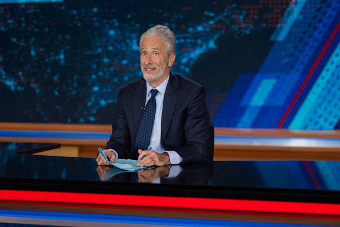 Jon Stewart speaking behind his desk on The Daily Show during a segment about the 2026 World Cup final.
