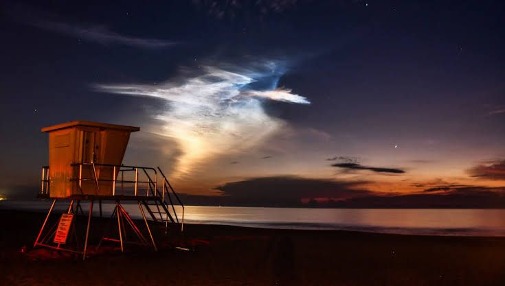 SpaceX Falcon 9 rocket ascending from Cape Canaveral creating a plume against the morning sky.