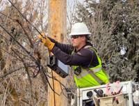 An Idaho Falls Fiber worker installing overhead fiber optic cable to expand high-speed internet service.