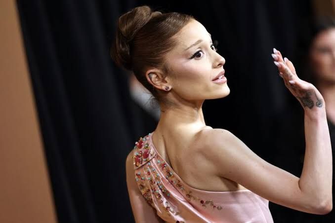 Ariana Grande performing on stage during her summer tour while fans watch from the front row.