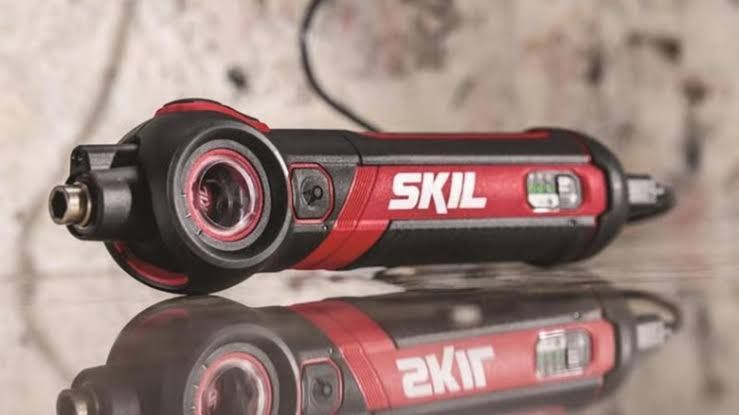 Close-up of a Skil 4V cordless electric screwdriver being used to tighten a small screw on a cabinet.