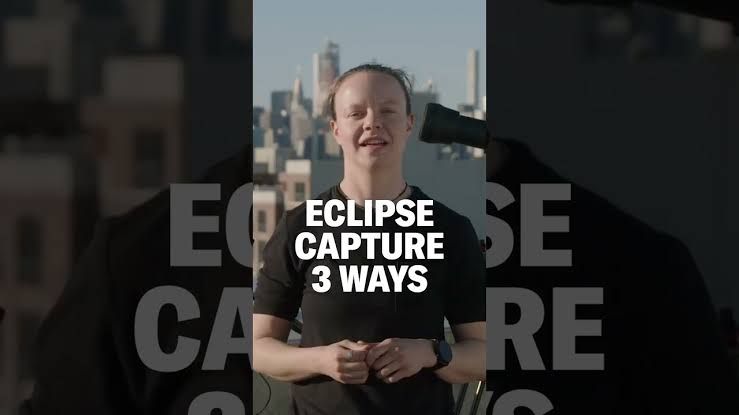 Lucie McCormick demonstrates camera positioning for solar eclipse photography in a field setting.
