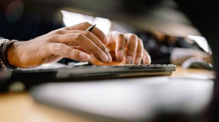 A close-up of a person's hands using a laptop keyboard to access an online gym booking system.