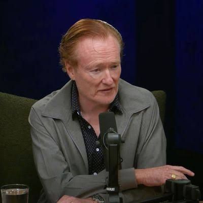 Conan O’Brien wearing his hair in a flat, slicked-back style while hosting his podcast.
