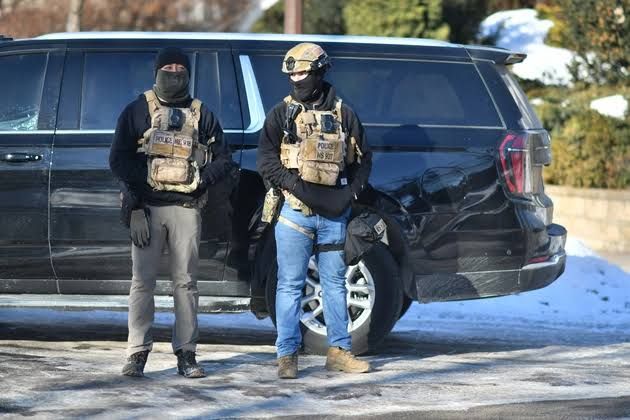 An ICE agent standing at an intersection in a Minnesota neighborhood during an enforcement operation.