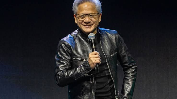 Nvidia CEO Jensen Huang presenting financial results on a screen showing stock growth and revenue projections.