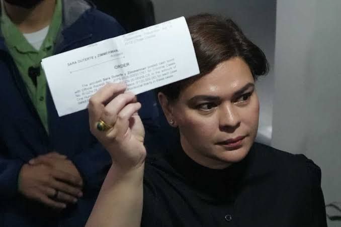 Philippine Vice President Sara Duterte shows a court document to reporters at the Quezon City justice hall.