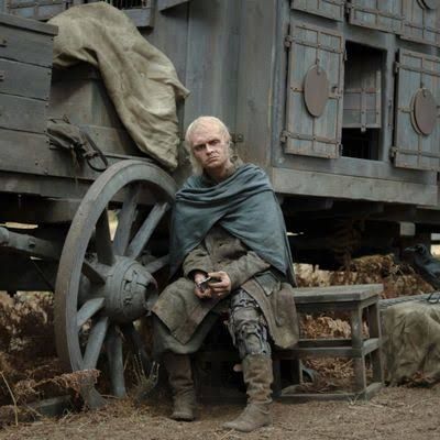Tom Glynn-Carney as King Aegon II Targaryen standing in a dim setting looking distressed.