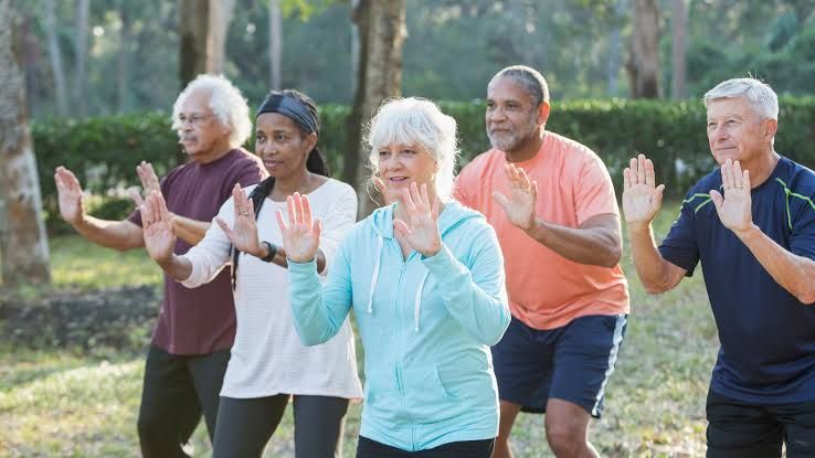 Group of people practicing Tai Chi in a park to improve balance and coordination.