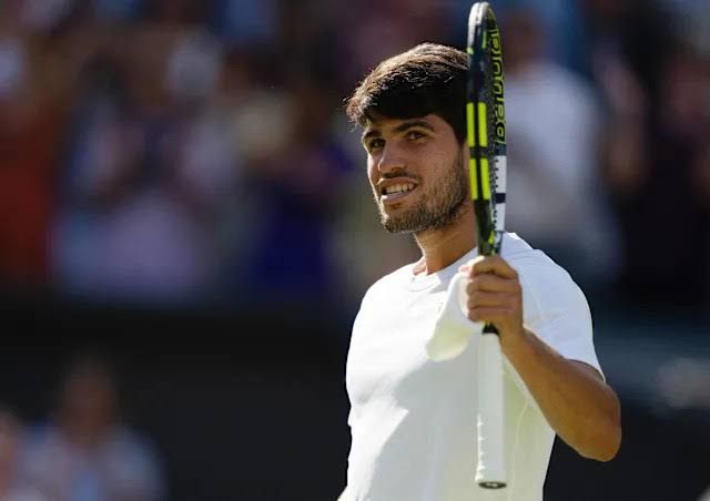 Carlos Alcaraz celebrates a tennis match victory while standing on a court.