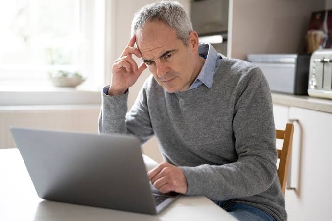 An investor checking financial charts on a laptop screen while looking worried, representing market uncertainty.
