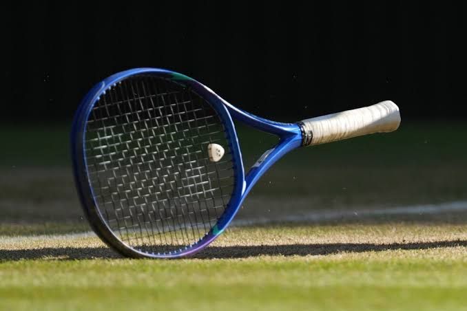 A professional tennis racket resting on the court surface at the Wimbledon Championships.