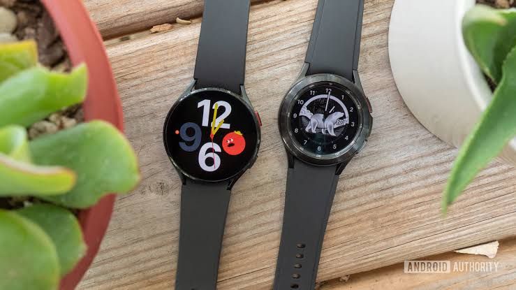 Samsung Galaxy Watch 4 and Classic models resting on a wooden surface.