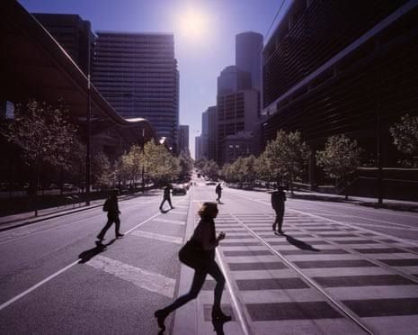 Silhouettes of people walking through an urban Melbourne street during the day.