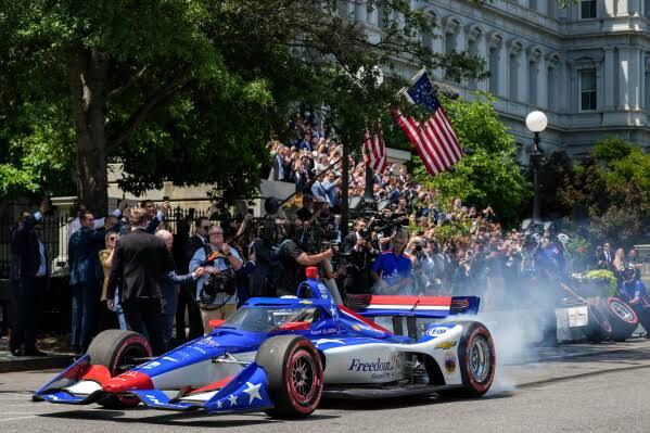 IndyCar race car driving on West Executive Drive during an event to promote the upcoming Freedom 250 Grand Prix.