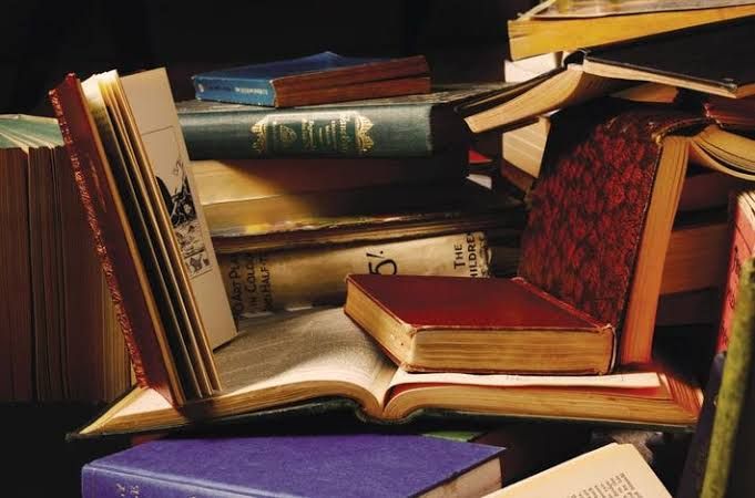 A stack of old, leather-bound books sitting on a shelf as part of a collection being targeted for scanning.