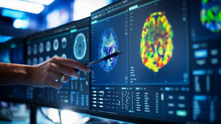 A medical professional analyzing a CT scan on a monitor alongside an AI-powered diagnostic software interface.