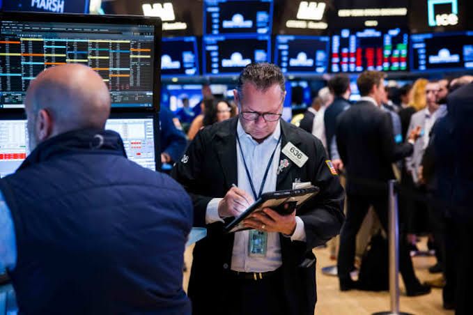 Traders monitor stock price displays at the New York Stock Exchange during a busy trading session.