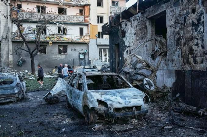 Local residents walk through debris in a Kyiv street near a large impact crater following a Russian missile attack.