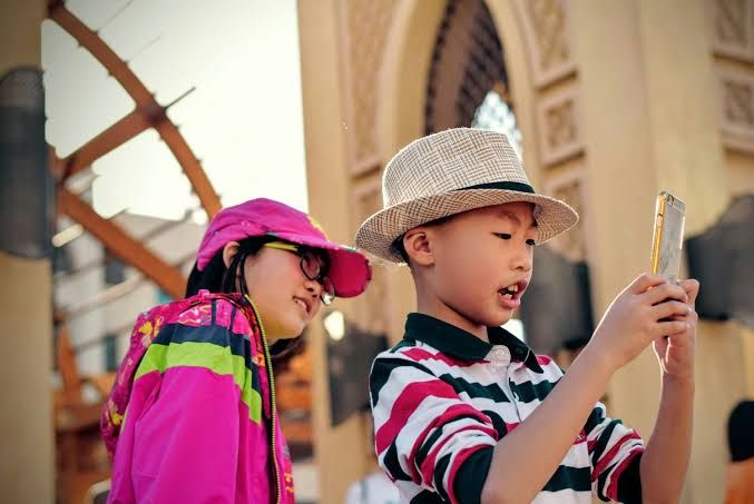 Children looking at mobile phones, representing the next generation of digital-native financial users.