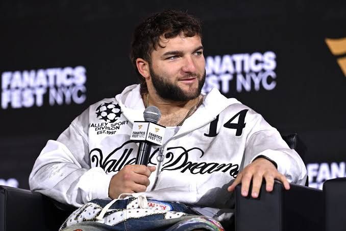 Cam Skattebo standing at a press event wearing a Giants jersey after his viral backflip attempt at Fanatics Fest.