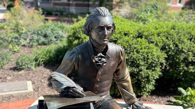 A bronze statue of Thomas Jefferson seated on a bench with a quill, installed in the White House Rose Garden.