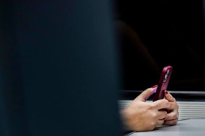Woman using a smartphone on a train, representing mobile app usage and connection trends.