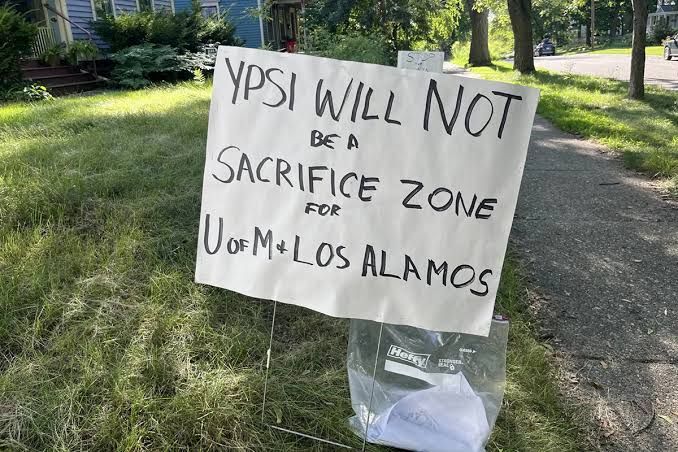 Protest sign on a residential lawn in Ypsilanti reading Ypsi will not be a sacrifice zone for U of M.