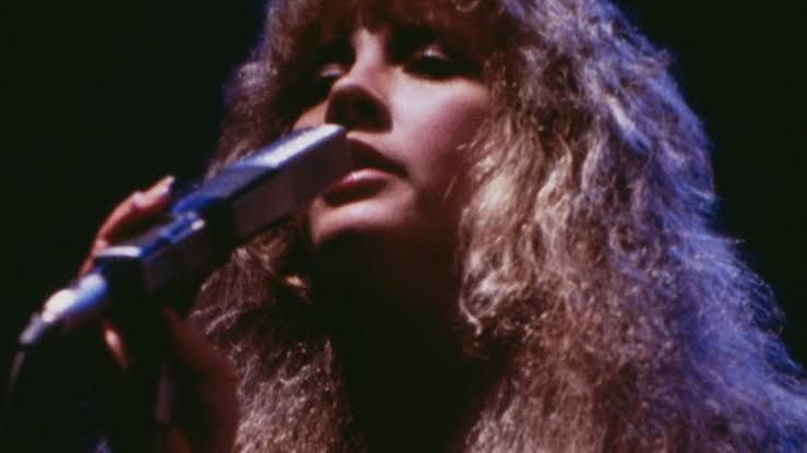 Stevie Nicks performing with Fleetwood Mac members John McVie, Christine McVie, Lindsey Buckingham, and Mick Fleetwood.