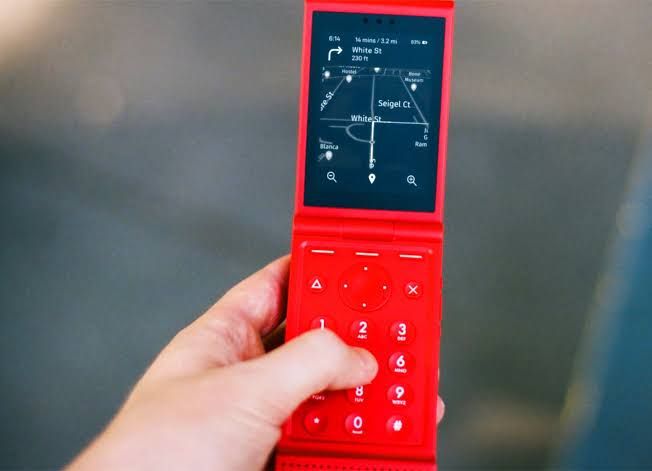 A close-up of the Light Flip phone showing its minimalist, text-based user interface on a small OLED screen.