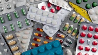 Close-up of blister packs and medicine bottles on a white surface representing NHS pharmacy waste.