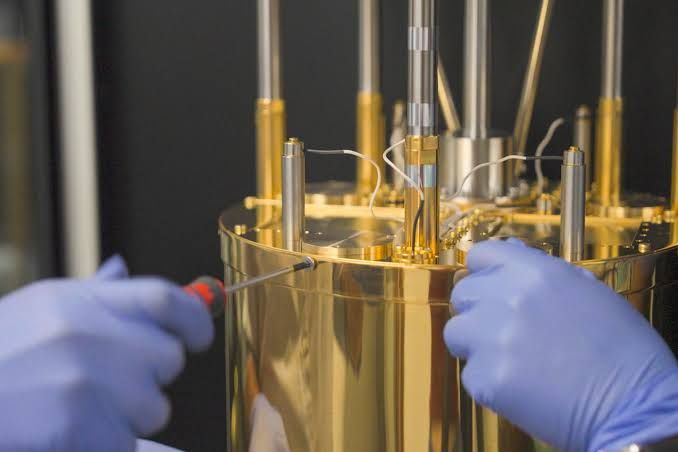 Researchers operating a 5-qubit superconducting quantum processor chip in a laboratory setting.