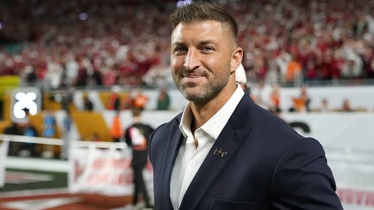Tim Tebow signs a full-sized taxidermied alligator for fans during an appearance at Fanatics Fest.